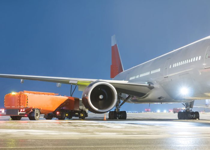 Airfield tanker refuels a wide-body passenger aircraft on the night airport apron